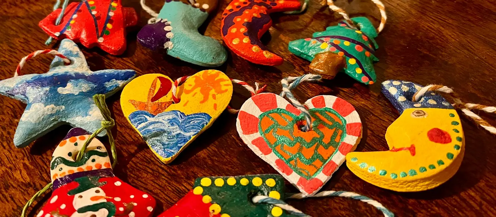 Hand-painted homemade ornaments shaped like stars, hearts and moons on a wooden table